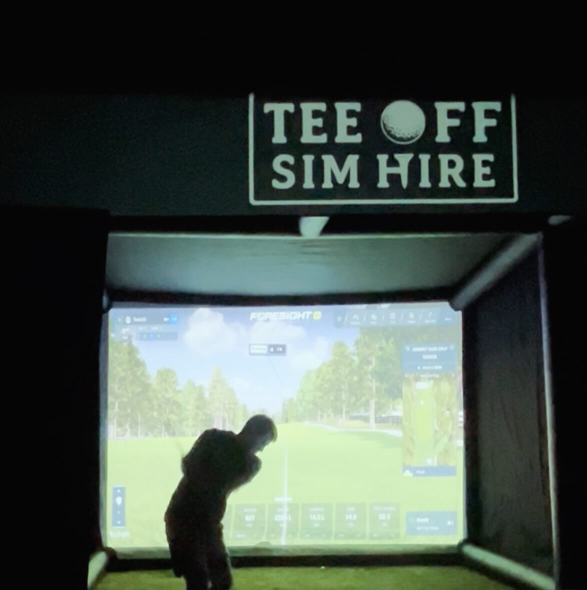 Player mid-swing inside a Tee Off Sim Hire booth